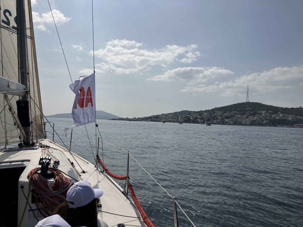 Yarım günlük şirket yelken etkinliğinde ekip üyeleri eğitmen eşliğinde tekneyi yönetiyor