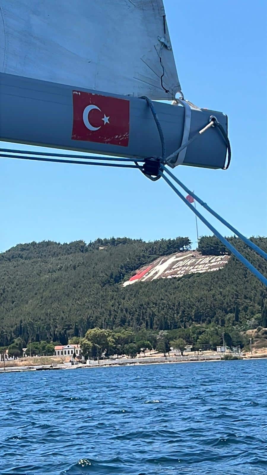 Açık deniz yelken yarışında Çanakkale Boğazı geçişinde Dur Yolcu kitabesi ve bumbada Türk bayrağı